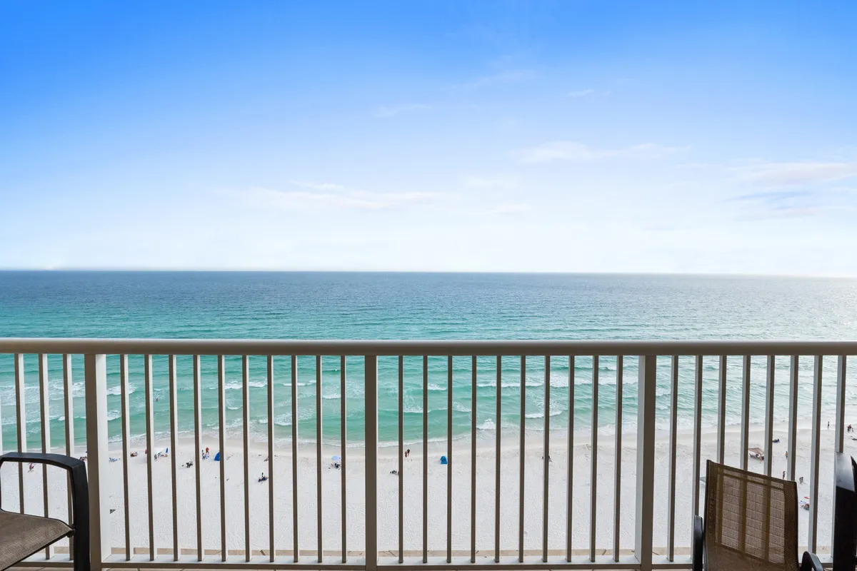 This image showcases a stunning ocean view from a furnished balcony, with the blue sky and beach stretching out beyond the railing. It captures the experience of enjoying group meals or evening drinks while overlooking the Gulf, reinforcing the waterfront and gathering aspects described in the section.